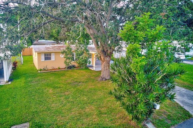 view of front of house with driveway, a front yard, fence, and stucco siding