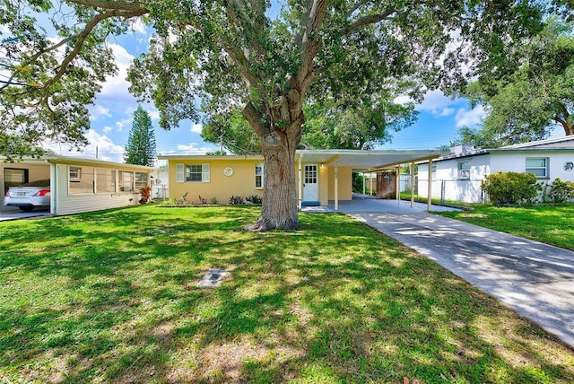 single story home featuring a carport, concrete driveway, a front lawn, and stucco siding