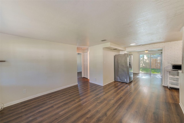 unfurnished living room with visible vents, dark wood finished floors, a textured ceiling, and baseboards