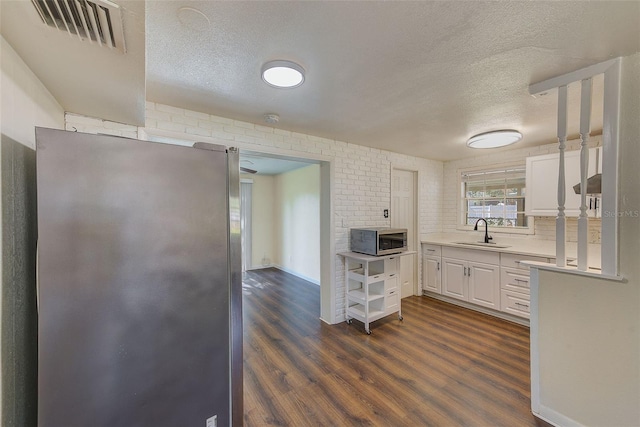 kitchen with stainless steel appliances, light countertops, visible vents, white cabinetry, and a sink