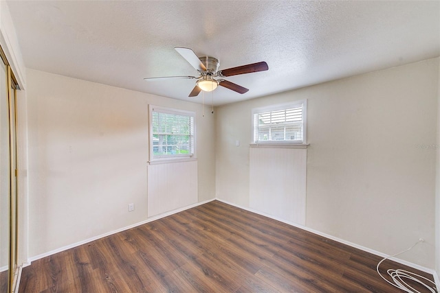 unfurnished room featuring ceiling fan, a textured ceiling, baseboards, and dark wood-style flooring