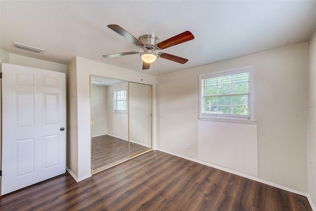 unfurnished bedroom featuring baseboards, visible vents, ceiling fan, dark wood-style flooring, and a closet