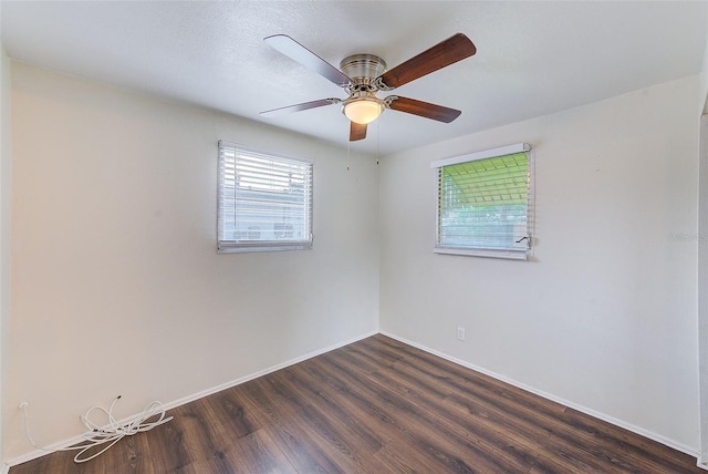 unfurnished room featuring dark wood-style flooring, a ceiling fan, and baseboards