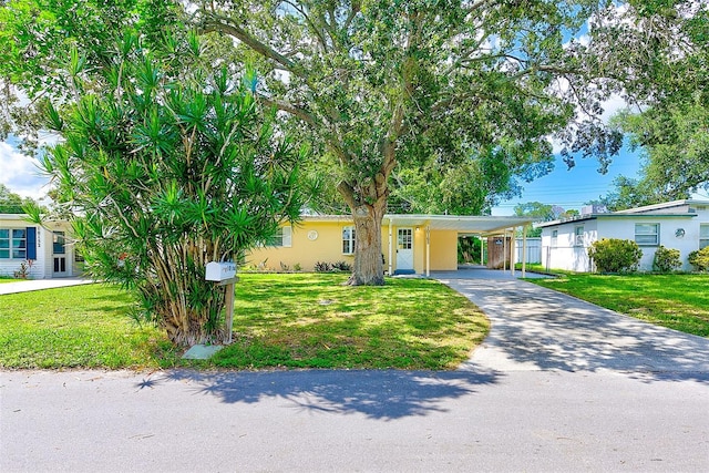 ranch-style house with a front yard, driveway, an attached carport, and stucco siding