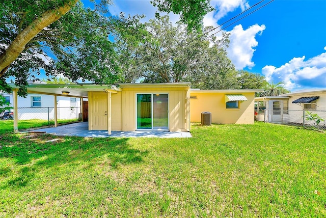 back of house with a carport, fence, central AC, and a yard