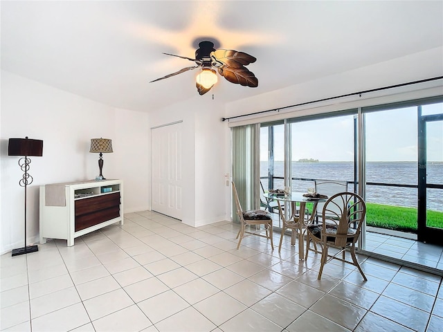 tiled dining room featuring ceiling fan and a water view