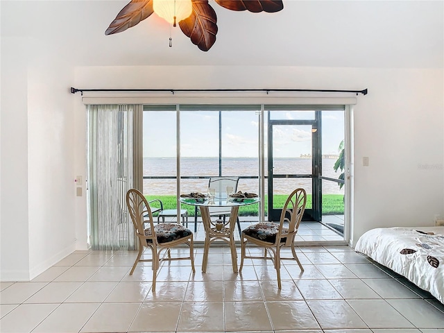 tiled dining area featuring ceiling fan and a water view