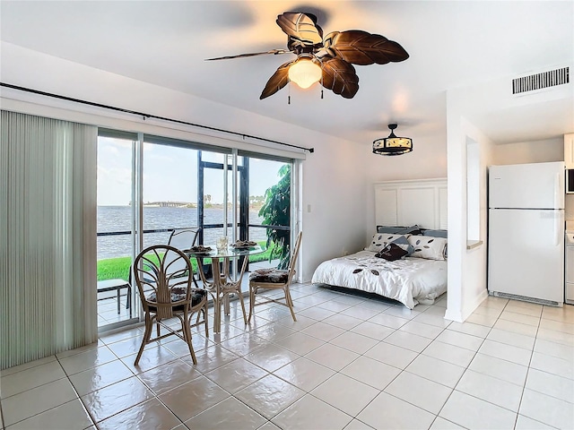 bedroom with ceiling fan, white refrigerator, a water view, access to exterior, and light tile patterned flooring