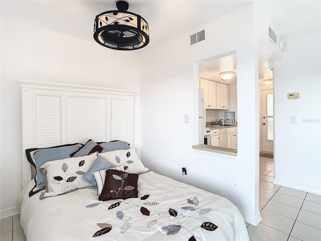 tiled bedroom with sink and white refrigerator