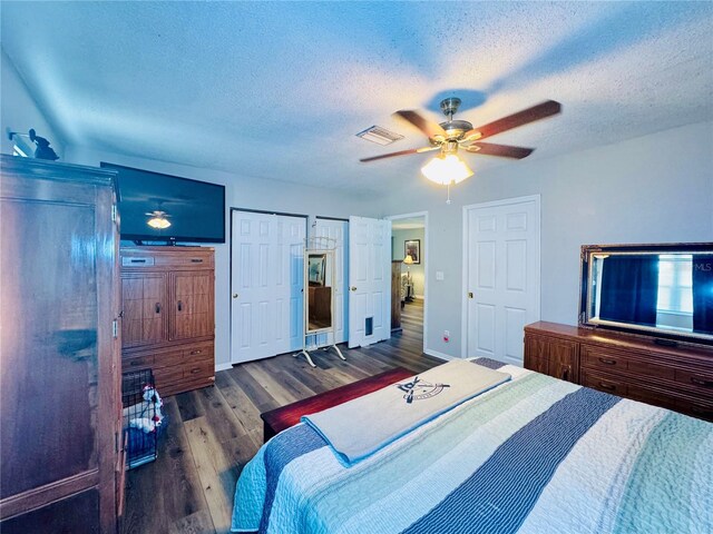 bedroom with visible vents, a textured ceiling, wood finished floors, and a ceiling fan