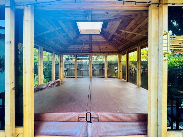 unfurnished sunroom with vaulted ceiling with skylight