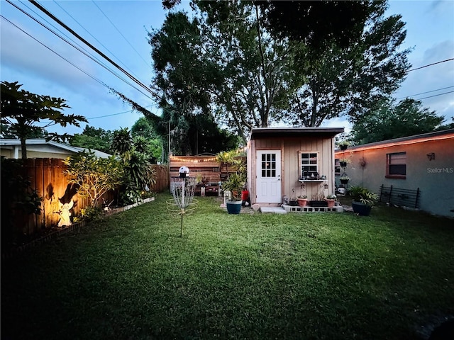 back of property with a fenced backyard, an outbuilding, and a yard