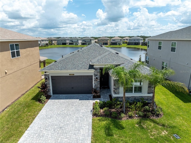 view of front of property featuring a garage, a front yard, and a water view