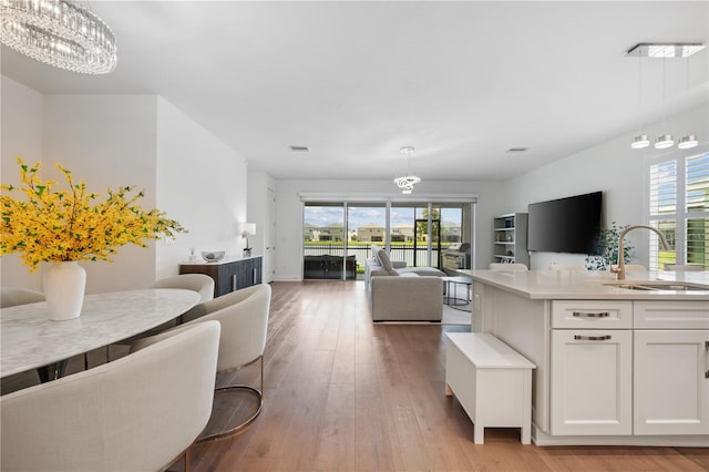 living room featuring a notable chandelier, sink, and light hardwood / wood-style flooring