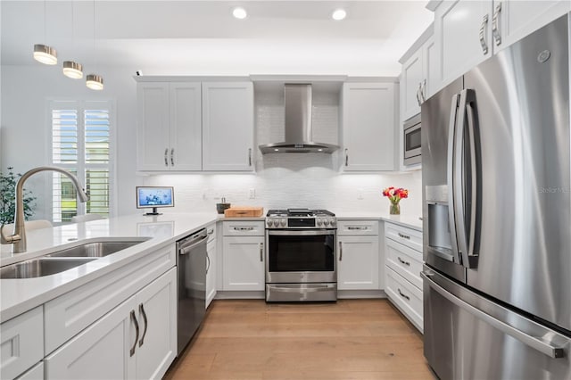 kitchen featuring sink, appliances with stainless steel finishes, white cabinetry, and wall chimney exhaust hood