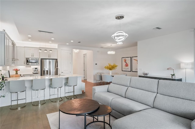 living room with an inviting chandelier and dark wood-type flooring