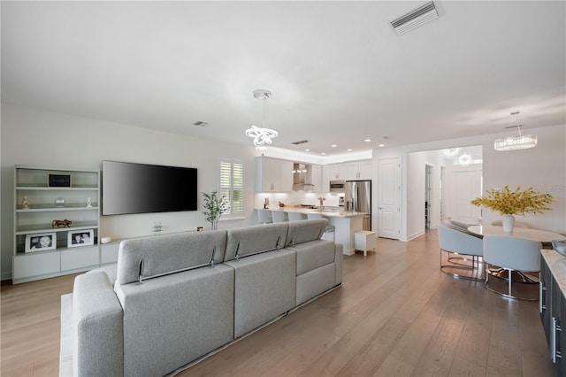 living room with light wood-type flooring and a chandelier