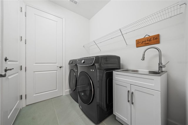 laundry area featuring light tile patterned flooring, sink, cabinets, and washer and clothes dryer