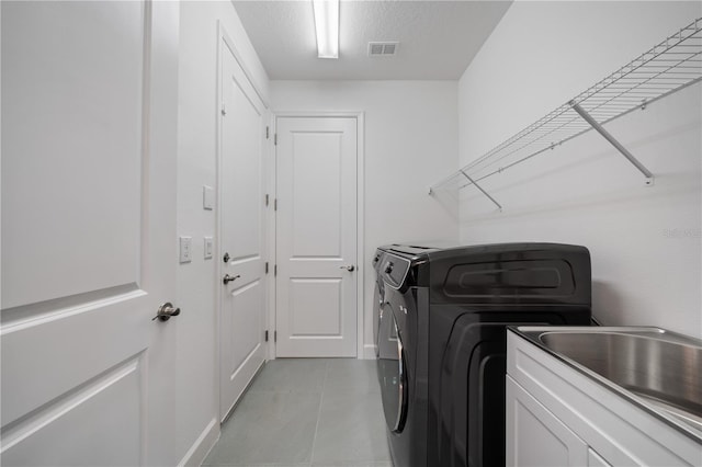 laundry area featuring independent washer and dryer, light tile patterned floors, sink, a textured ceiling, and cabinets