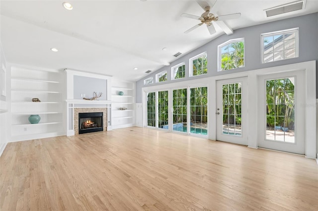 106 19th Ave, St Pete Beach, FL 33706 - unfurnished living room featuring vaulted ceiling, light wood-style flooring, a warm lit fireplace, ceiling fan, and built in features