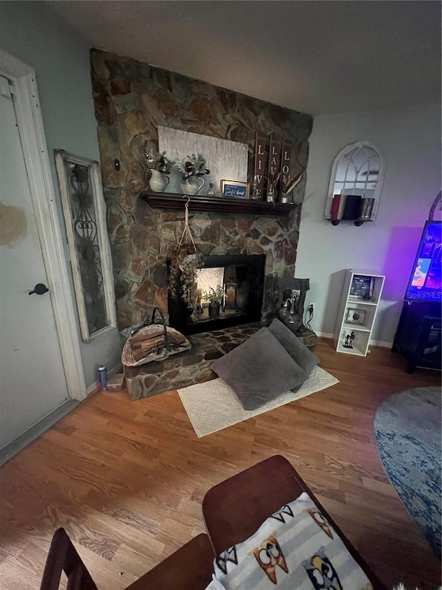 living room featuring wood-type flooring and a stone fireplace