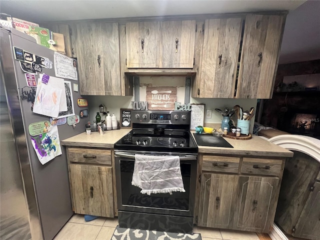 kitchen featuring stainless steel refrigerator, light tile patterned floors, and black range with electric stovetop