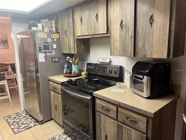 kitchen featuring black / electric stove, stainless steel fridge, and light tile patterned floors