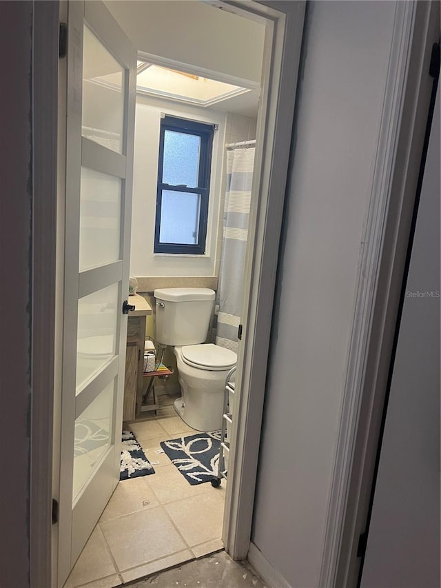 bathroom featuring tile patterned flooring, walk in shower, and toilet