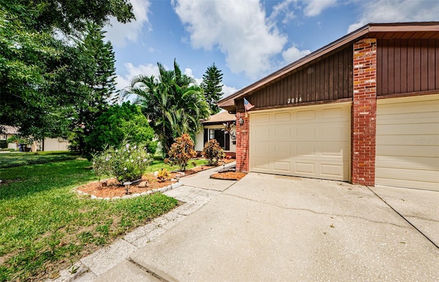 view of front of home featuring brick siding, driveway, and a front yard