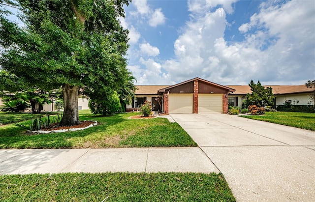 view of front of house with brick siding, an attached garage, driveway, and a front yard