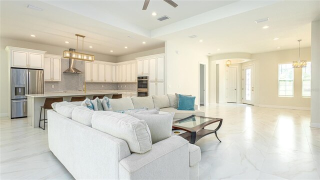 living room with light tile patterned flooring and ceiling fan with notable chandelier