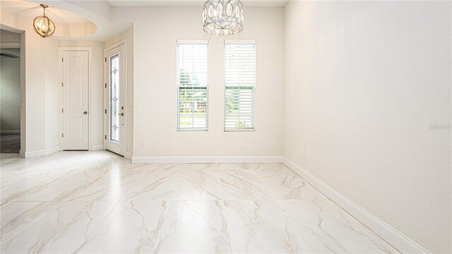 tiled empty room featuring a chandelier