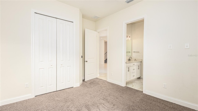 unfurnished bedroom featuring ensuite bath, sink, and light carpet