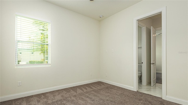 unfurnished bedroom featuring ensuite bathroom and light carpet