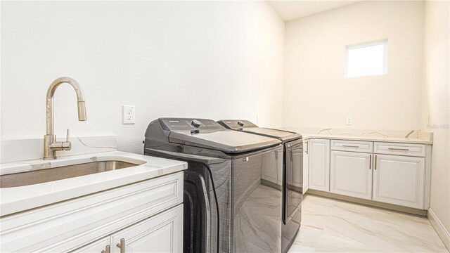 washroom featuring cabinets, washing machine and dryer, light tile patterned floors, and sink