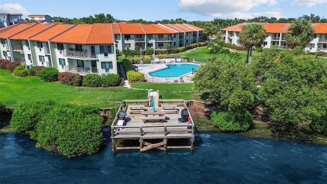 exterior space featuring a community pool, a water view, a lawn, and a balcony