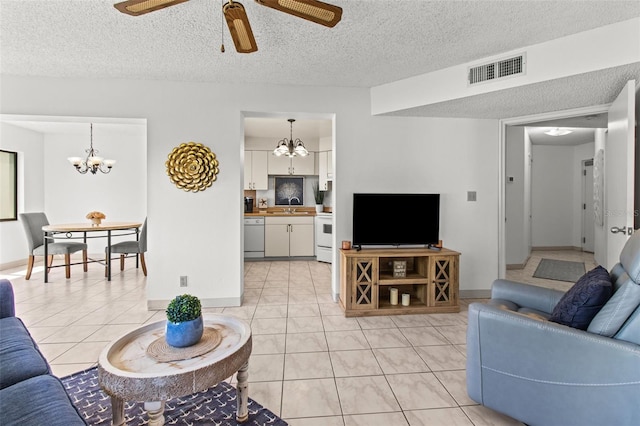 living room featuring a textured ceiling, sink, ceiling fan with notable chandelier, and light tile patterned flooring