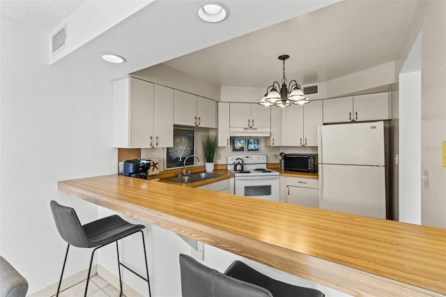 kitchen featuring a notable chandelier, white appliances, sink, a breakfast bar area, and white cabinets