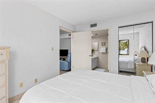 bedroom featuring ensuite bath, a textured ceiling, and a closet