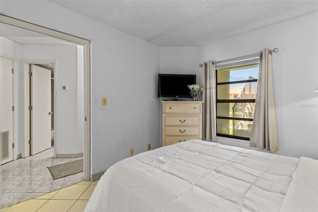 bedroom featuring a textured ceiling, light tile patterned flooring, and visible vents