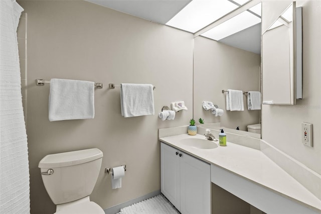 full bathroom featuring a skylight, curtained shower, toilet, vanity, and baseboards