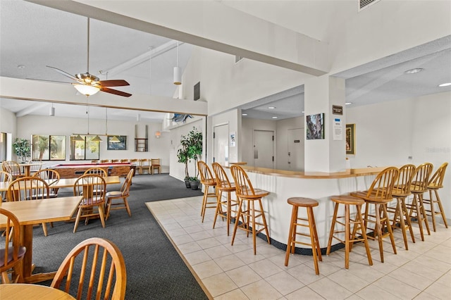 kitchen with ceiling fan, high vaulted ceiling, a breakfast bar, and light tile patterned flooring