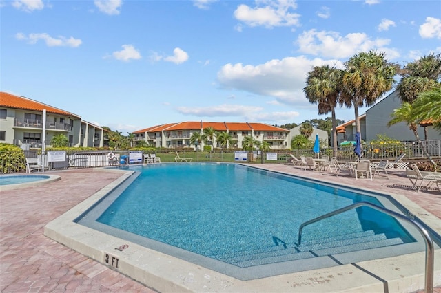 community pool featuring a patio area, a residential view, and fence