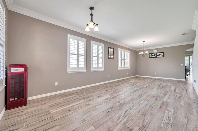 spare room with light hardwood / wood-style floors, ornamental molding, and a notable chandelier