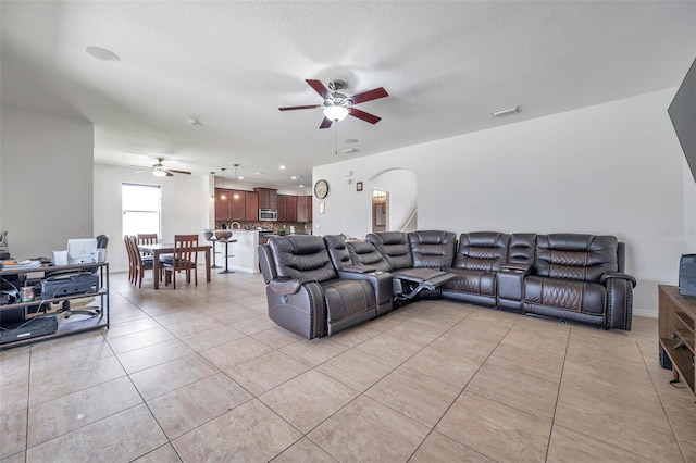 living room featuring a textured ceiling, light tile patterned floors, and ceiling fan