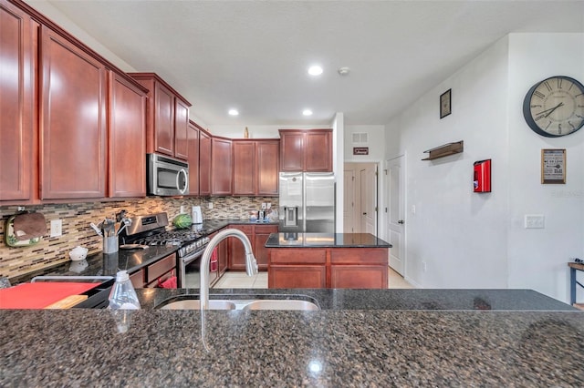 kitchen featuring dark stone countertops, stainless steel appliances, sink, and decorative backsplash