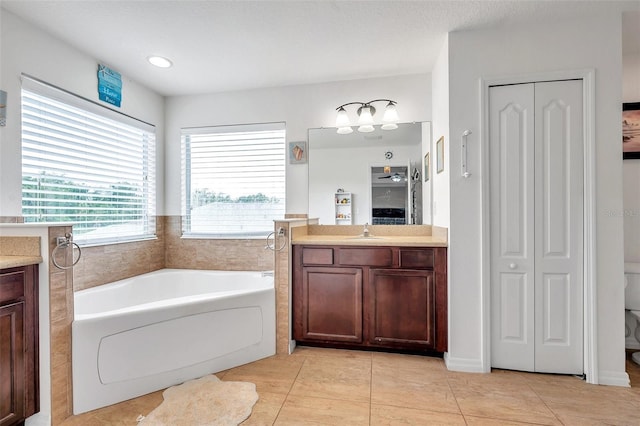 bathroom featuring a tub to relax in, vanity, a textured ceiling, tile patterned flooring, and toilet