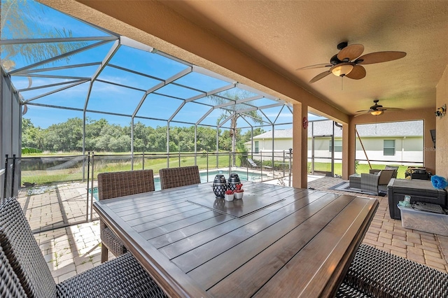 view of patio featuring ceiling fan and glass enclosure