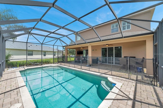 view of pool with a patio, glass enclosure, and ceiling fan