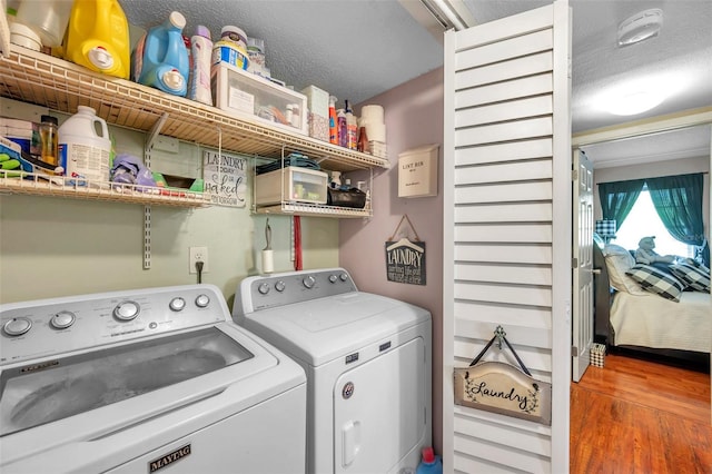 washroom with washing machine and clothes dryer, a textured ceiling, and hardwood / wood-style floors